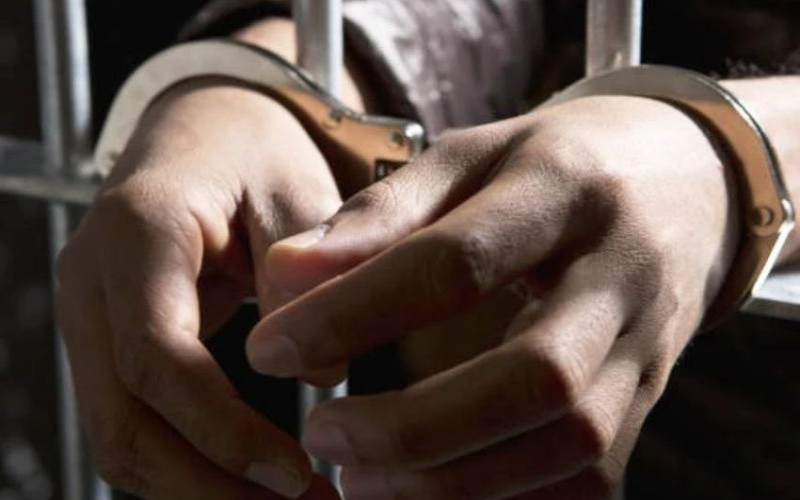 A person handcuffed in a jail cell FILE